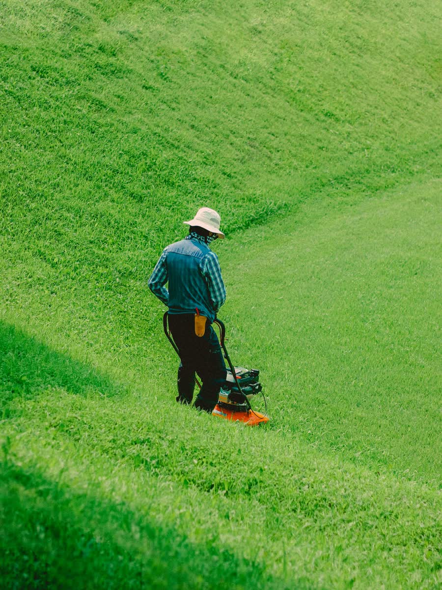 Crew member mowing a deep green lawn